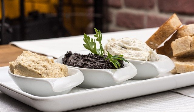 three dips in white bowls with bread