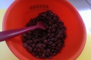 chocolate callets in a plastic bowl with stirrer