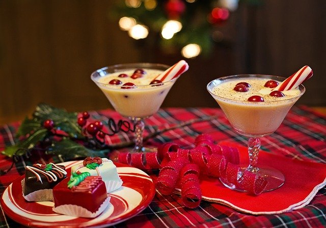 Snowball cocktails with cherries and small cakes on a checked tablecloth