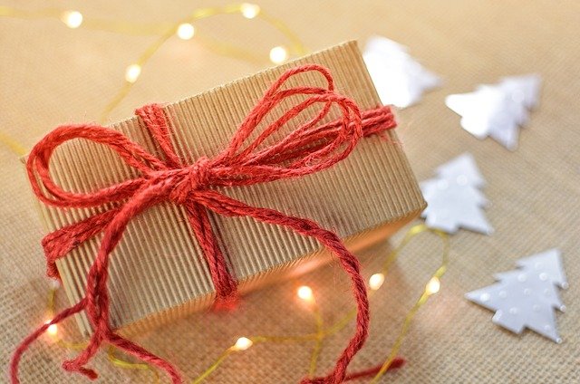 Cardboard box tied with red string, on a table with twinkly lights and tree decorations