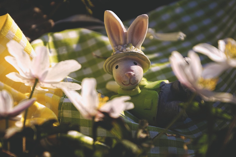 Easter Bunny sitting on a tablecloth with spring flowers